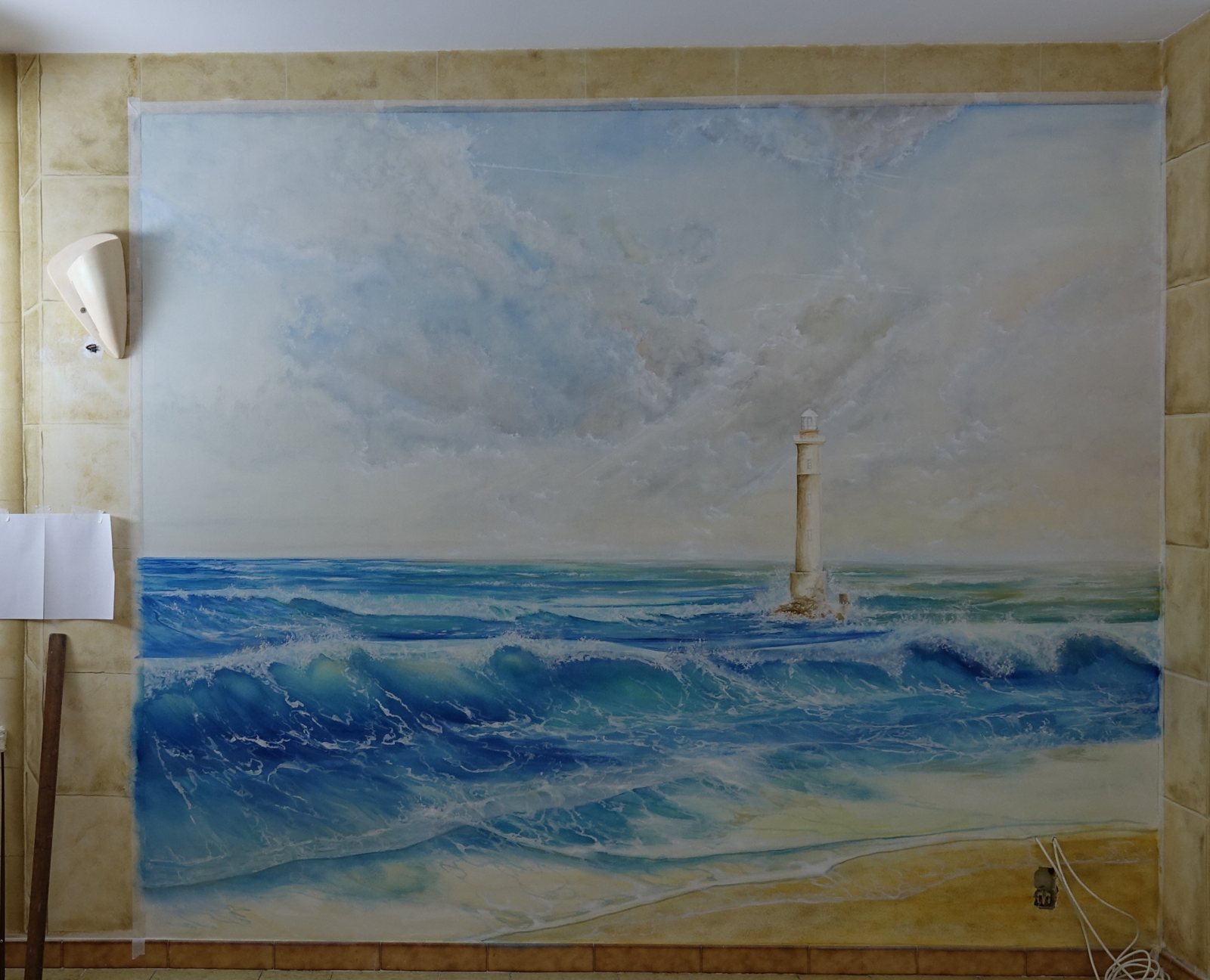 Décor peint en trompe-l'œil : phare dans les vagues sous un ciel nuageux, encadré de fausses pierres